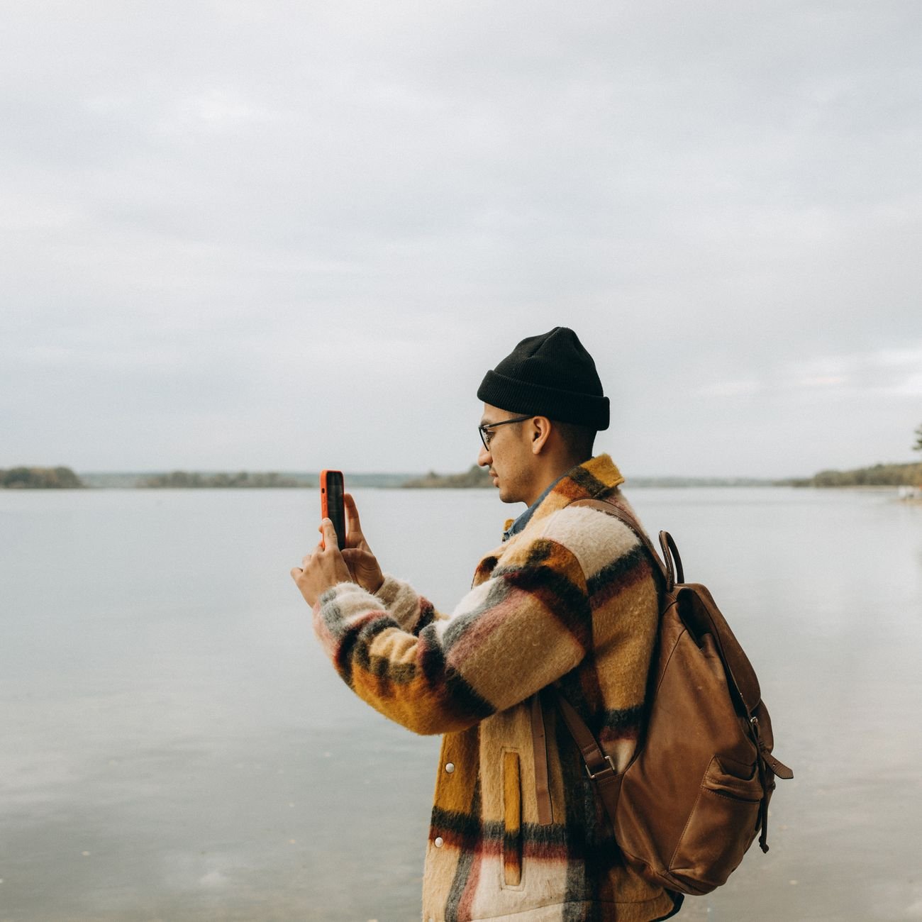 A man using his smartphone outdoors near a serene lake